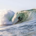 Surfer riding a massive wave in California, showcasing thrilling ocean action and skill.
