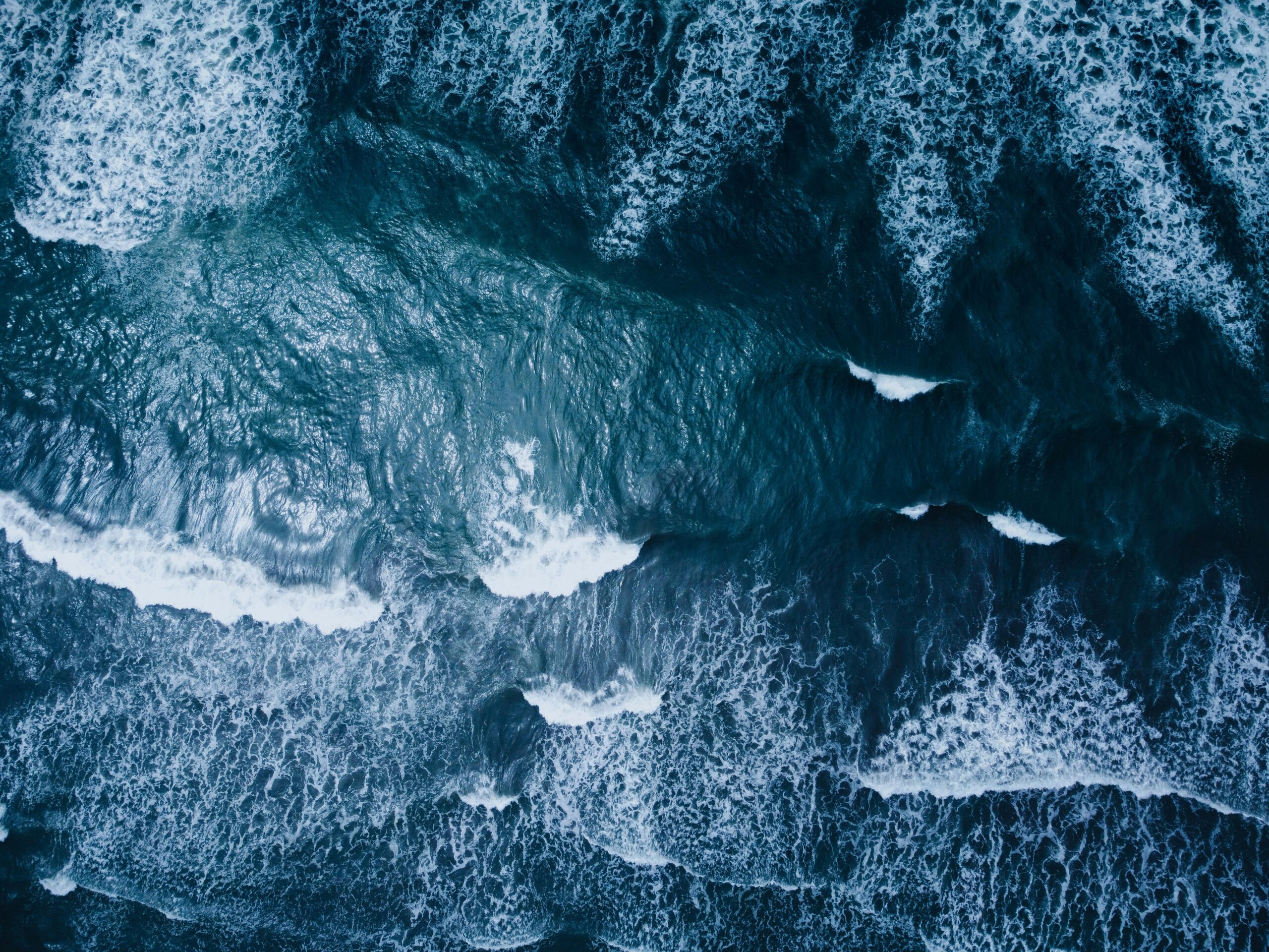 A stunning aerial shot of ocean waves crashing onto the shore, showcasing nature's power and beauty.