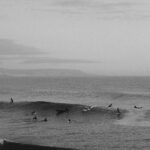 Black and white photo of surfers catching waves at Imsouane, Souss-Massa, Morocco.